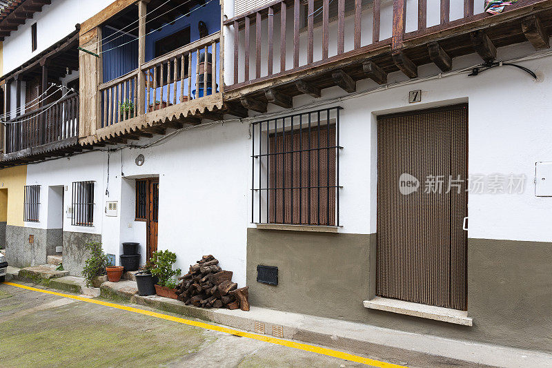 埃斯特雷马杜拉卡塞雷斯Villanueva de la Vera镇一所带有传统木制阳台的房子的入口处，一堆木柴。